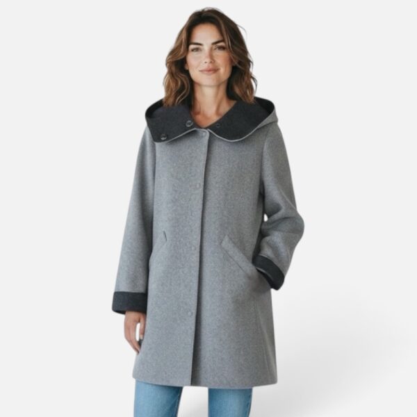 Bild 1: Frau trägt grauen Irlanda Hoody Mantel mit Kapuze und Knopfleiste, Frontalansicht • Bild 2: Nahaufnahme der Kapuze mit kontrastierendem Futter und Druckknöpfen • Bild 3: Seitliche Ansicht des grauen Wintermantels mit lockerem Schnitt • Bild 4: Frau im Irlanda Mantel in Bewegung, Dreiviertelansicht • Bild 5: Rückansicht des Mantels mit Kapuze und umgeschlagenen Ärmelbündchen • Bild 6: Freigestellte Produktansicht des Irlanda Hoody Mantels in Grau