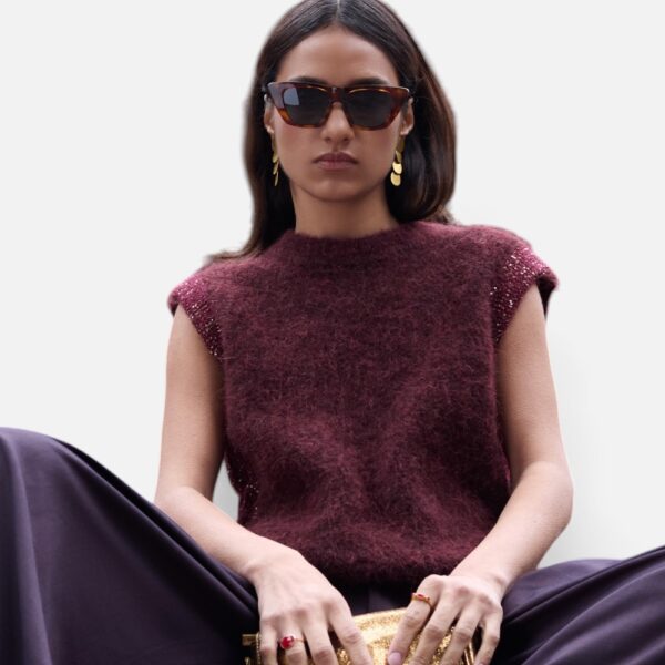 1. Frau mit Sonnenbrille trägt weinroten Strickpullunder mit Glitzerdetail, sitzend mit goldener Clutch 2. Nahaufnahme weinroter Strickpullunder mit Glitzer-Akzenten an der Schulter, Frontalansicht 3. Ganzkörperansicht weinroter Strickpullunder kombiniert mit weiter dunkler Stoffhose 4. Frau im weinroten Strickpullunder mit Sonnenbrille sitzt auf Treppenstufen, urbaner Hintergrund 5. Seitenansicht weinroter Strickpullunder mit weiter Stoffhose, Glitzerdetail an der Seitennaht sichtbar 6. Rückansicht weinroter Strickpullunder mit weiter Stoffhose 7. Ganzkörper-Frontalansicht weinroter Strickpullunder mit goldener Clutch, gehend 8. Weinroter Strickpullunder über gestreiftem Longsleeve kombiniert, Layering-Look 9. Freisteller weinroter Strickpullunder auf weißem Hintergrund